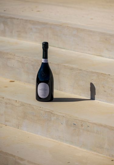 A bottle of Domaine Evremond Classic Cuvée on stone steps